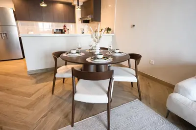 a dining room table with chairs and a kitchen at Upscale Modern 2-Bedroom with Elegant Interiors in Dubai
