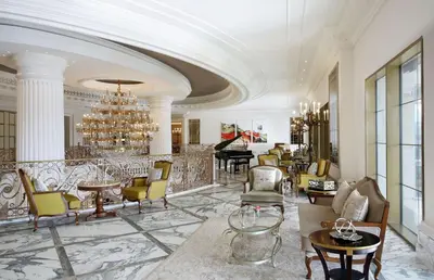 a lobby with a chandelier and chairs and a piano at Al Habtoor Palace - Preferred Hotels & Resorts in Dubai