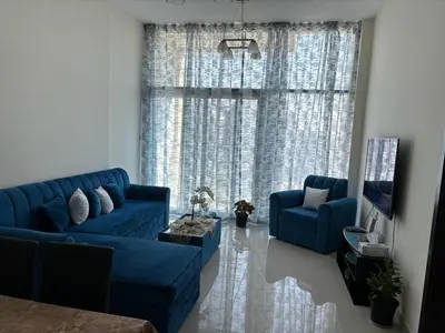 a living room with blue couches and a large window at شقة غرفة وصالة Apartment one bad room in Dubai
