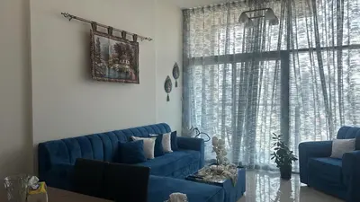 a living room with blue couches and a large window at شقة غرفة وصالة Apartment one bad room in Dubai