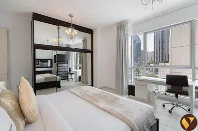 a bedroom with a bed and a desk with a television at Vogue Downtown Burj Residence Near Dubai Mall and Burj Khalifa, Three Bedroom Plus Maid's room Apartment with Balcony and City View, Access to all Amenities in Dubai