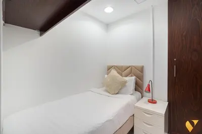 a bedroom with a white bed and a wooden cabinet at Vogue Downtown Burj Residence Near Dubai Mall and Burj Khalifa, Three Bedroom Plus Maid's room Apartment with Balcony and City View, Access to all Amenities in Dubai