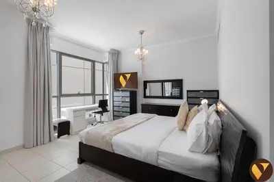 a bedroom with a bed and a desk and a window at Vogue Downtown Burj Residence Near Dubai Mall and Burj Khalifa, Three Bedroom Plus Maid's room Apartment with Balcony and City View, Access to all Amenities in Dubai