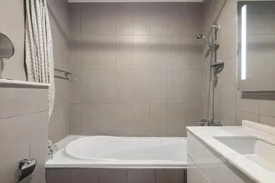a white bathroom with a tub and a sink at Palm Jumeirah Luxury Direct Beach Access and Views in Dubai