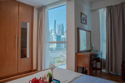 a bedroom with a bed and a desk and a large window at Stylish 1BR close to Metro and Dubai Marina in Dubai
