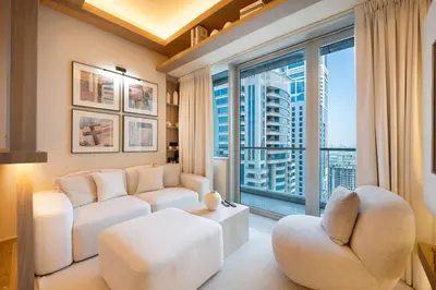 a living room with white furniture and a large window at Modern and Stylish 2-BR High Floor All Bills Included in Dubai