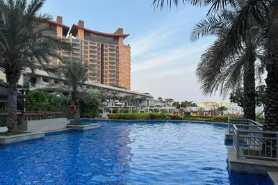 a swimming pool with a large building in the background at Modern & Bright 2 Bedroom Apartment at The Palm in Dubai