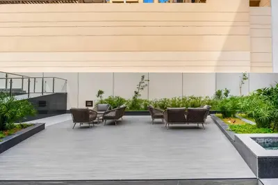a patio with wicker chairs and tables in a building at Vogue JVC Al Serh Residences Near Circle Mall, One Bedroom Plus Maid's room Apartment with Balcony and City View, Access to all Amenities in Dubai