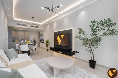a living room with a couch and a tv on a wall at Vogue JVC Al Serh Residences Near Circle Mall, One Bedroom Plus Maid's room Apartment with Balcony and City View, Access to all Amenities in Dubai