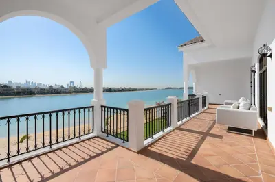 a white house with a balcony with a view of the water at Maison Privee - Villa on Beach with Private Pool The Palm Jumeirah in Dubai