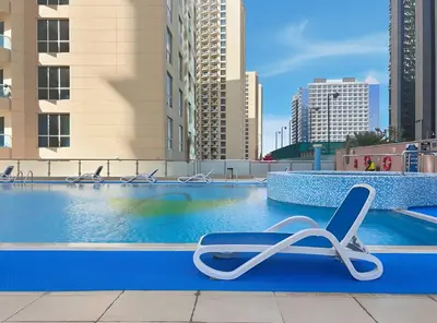 a swimming pool with a lounge chair in a city at Sunny Studio with Pool, Gym & Sauna in Dubai Escape in Dubai