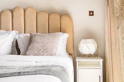 a bed with a large padded headboard next to a side table at Sunny Studio with Pool, Gym & Sauna in Dubai Escape in Dubai