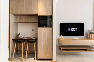 a room with a kitchen with a desk and a tv at Chic and Peaceful Studio with Balcony & Pool in JVC in Dubai