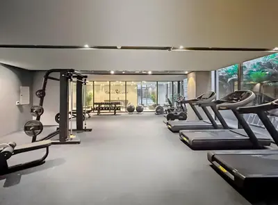 a gym with a row of treadmills and machines at Chic and Peaceful Studio with Balcony & Pool in JVC in Dubai