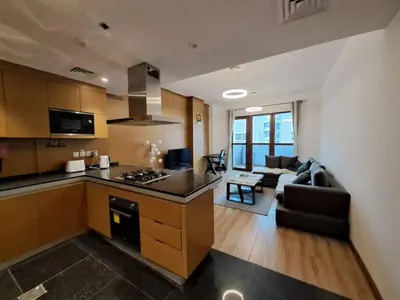 a kitchen and a living room with a couch and a kitchen and a living room at Modern One-Bedroom Apartment King and Queen Beds Two Bathrooms in Dubai