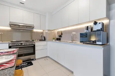 a kitchen with white cabinets and a stove top oven at Safi Apartments 2A, Town Square - 2 Bedroom Apartment - Allsopp & Allsopp in Dubai