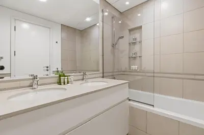 a white bathroom with two sinks and a shower at Safi Apartments 2A, Town Square - 2 Bedroom Apartment - Allsopp & Allsopp in Dubai