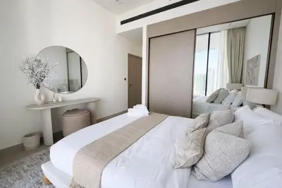 a white bedroom with a large bed and a mirror at Tranquil 1BR with Private Plunge Pool in Dubai