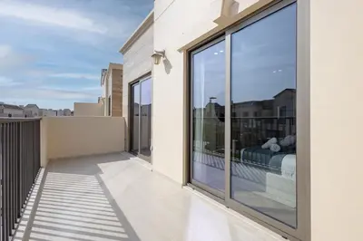 a balcony with large glass windows and a bed at Jasmine Lane, JGE - 3 Bedroom with maids' room Townhouse - Allsopp & Allsopp in Dubai