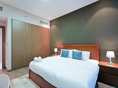 a bedroom with a large white bed with blue pillows at Bright & Spacious 2-Bedroom Apartment Al furjan-706 in Dubai