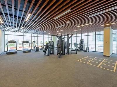 a gym with cardio equipment in a large room with windows at Bright & Spacious 2-Bedroom Apartment Al furjan-706 in Dubai