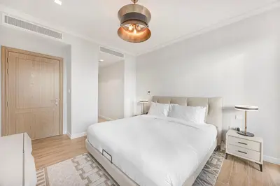a white bedroom with a large bed and a lamp at Daniels 3BR Villa plus M at La Mer With Beach Access in Dubai