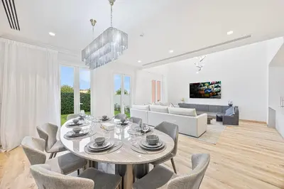 a white living room with a table and chairs at Daniels 3BR Villa plus M at La Mer With Beach Access in Dubai