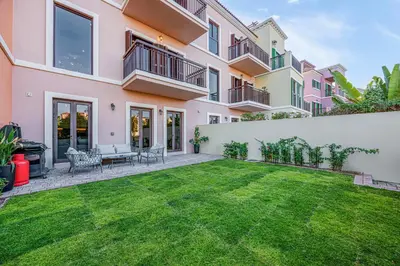 a backyard with a lawn in front of a house at Daniels 3BR Villa plus M at La Mer With Beach Access in Dubai