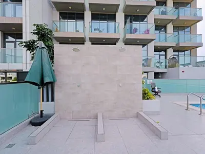 a building with a green umbrella in a courtyard at Modern 1-Bedroom Apartment in Sepcoo Residence-1005 in Dubai
