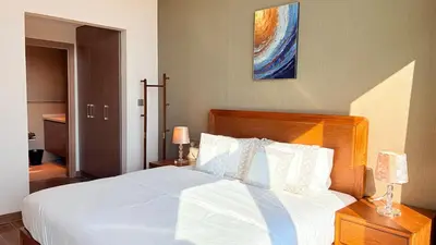 a bedroom with a white bed with a wooden headboard at Ready-to-Move 1-Bedroom in Al Furjan-103 in Dubai