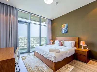 a bedroom with a bed and a desk and a large window at Spacious 2-Bedroom Apartment in Al Furjan-1010 in Dubai