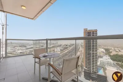 a balcony with a table and chairs and a view of a city at Vogue JVT Novotel Near Springs Souk Mall, One Bedroom Apartment with Large Balcony and Vibrant Community view, Access to all Amenities in Dubai