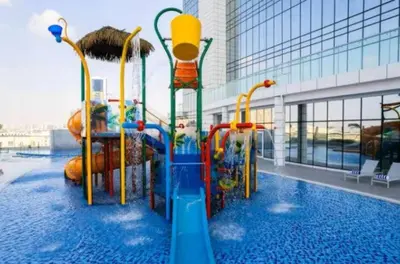 a water slide in a pool in a building at Vogue JVT Novotel Near Springs Souk Mall, One Bedroom Apartment with Large Balcony and Vibrant Community view, Access to all Amenities in Dubai