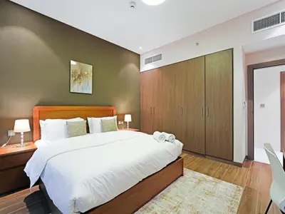 a bedroom with a large white bed and a wall at Well-Maintained 2-Bedroom Apartment Al Furjan-207 in Dubai