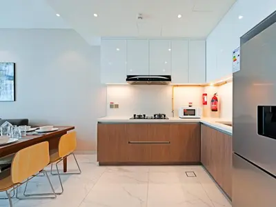 a kitchen with white cabinets and a table with chairs at Well-Maintained 2-Bedroom Apartment Al Furjan-207 in Dubai