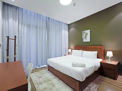 a bedroom with a large white bed and a table at Well-Maintained 2-Bedroom Home in Community-410 in Dubai