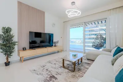 a living room with a tv and a large window at TRPS - Grand Bleu Tower 2, EMAAR Beachfront - Atlantis & Marina View, Private Beach, Furnished in Dubai