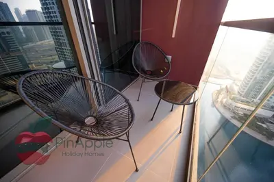 two chairs and a table on a balcony in a building at High Floor With Full Lake View in Dubai