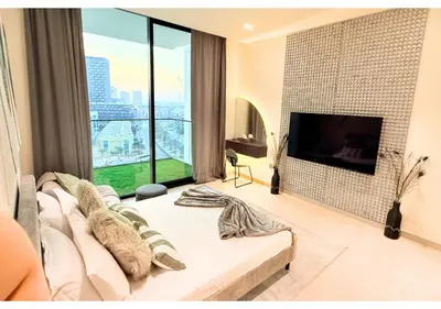 a living room with a couch and a flat screen tv at Chic Modern Studio Unit in JVC with 65 inch TV in Dubai