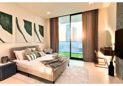 a bedroom with a bed and a large window at Chic Modern Studio Unit in JVC with 65 inch TV in Dubai