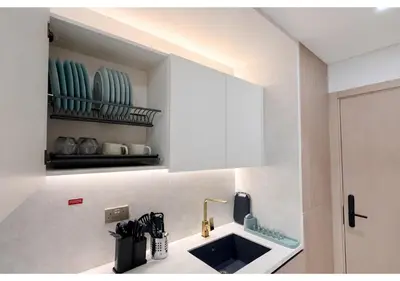 a kitchen with a sink and a white cabinet at Chic Modern Studio Unit in JVC with 65 inch TV in Dubai