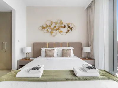 a bedroom with a large white bed with two towels at Brand New & Welcoming 2BDR In Forte Downtown 34 in Dubai