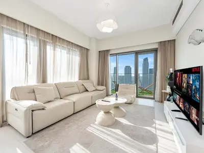a white living room with a couch and a tv at Burj Royale Collection by The Luxe Manor - Downtown Dubai in Dubai