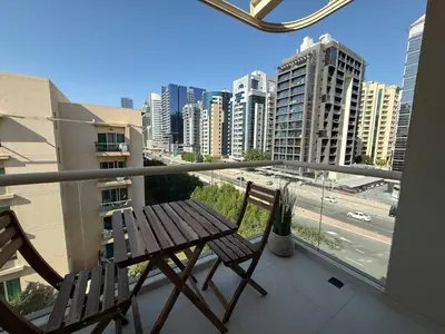 a balcony with a wooden bench and a view of a city at High End Upgraded 1BR Living in The Greens in Dubai