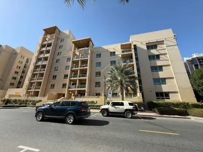 two cars parked in a parking lot in front of a building at High End Upgraded 1BR Living in The Greens in Dubai