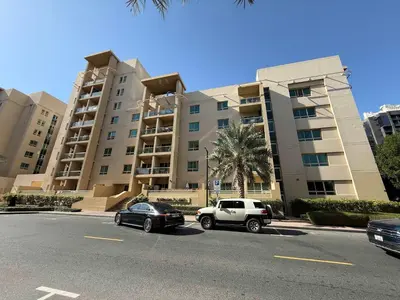 two cars parked in front of a large building at High End Upgraded 1BR Living in The Greens in Dubai