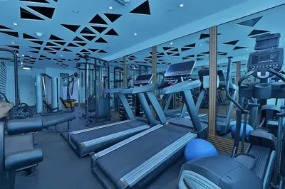 a gym with rows of treadmills and machines at The Eden Suite Modern Luxury Meets Cozy Comfort in Dubai