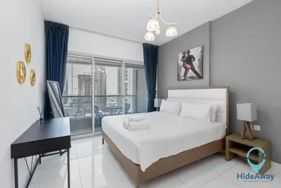 a bedroom with a bed and a desk and a window at Elegant 1BR l Steps to Metro l Free Parking in Dubai