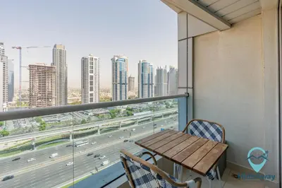 a table and chairs in a balcony with a view of a highway at Elegant 1BR l Steps to Metro l Free Parking in Dubai