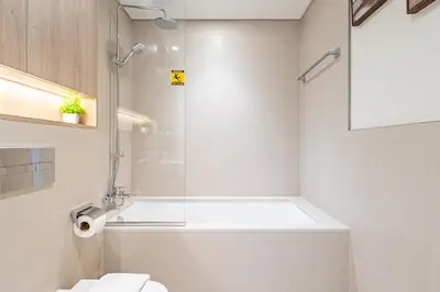 a white bathroom with a shower and a toilet at Superhost - 1BR Apartment , Pool & Gym , Near Dubai Hills Mall in Dubai